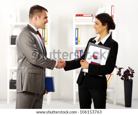 Business man and business women in the office standing and handshaking