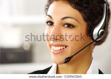 Young attractive brunette business girl standing and smiling with earphones on her ears close up
