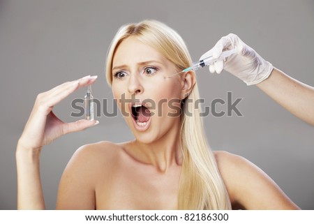 Young blonde getting an injection, with the scared expression on her face, looking at the vial