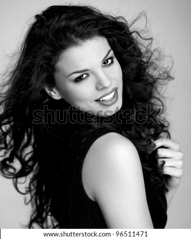 Black and white photo of an attractive curly haired brunette girl in red turtleneck sweater smiling