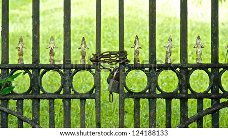 Chains and locks hold a rusting iron gate closed.