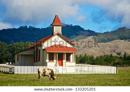 Antique school house sits in a meadow beneath the rolling hills of the central California coast.