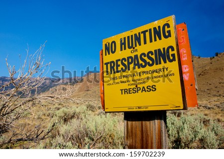 No Hunting or Trespassing sign warns people from crossing the fence in the West.