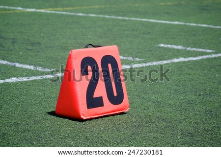 Orange yard marker designates the twenty yard line on a football field.
