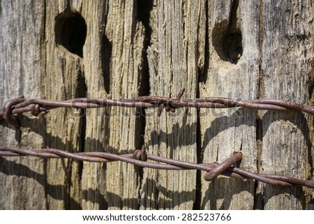 Rusting sharp metal points on fence with aging old wood.