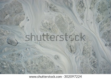 Pattern of silt and mud flow in dirty stream in Alaska.