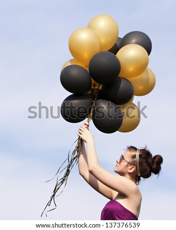 Balloons!  Attractive teen hanging on to a bunch of helium filled balloons.