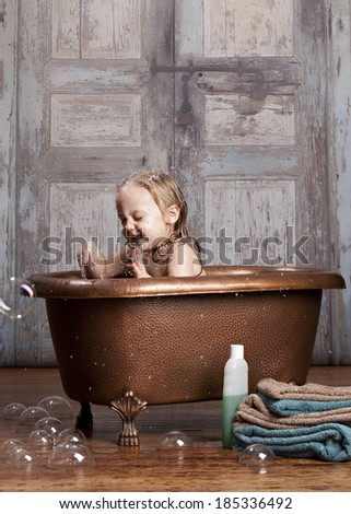 Bath time fun! Adorable toddler splashing in the tub.  Room for your text.