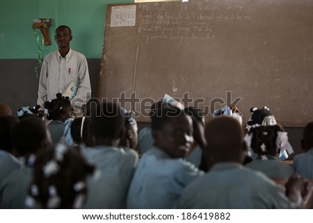 KOLMINY, HAITI - FEBRUARY 12, 2014 - Crowded Haitian classroom.  Shallow depth of field with focus on the teacher next to the blackboard.