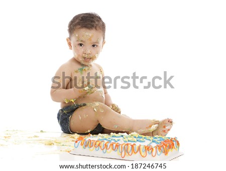 Cake smash.  Adorable baby boy covered in cake and frosting.  Isolated on white with room for your text.