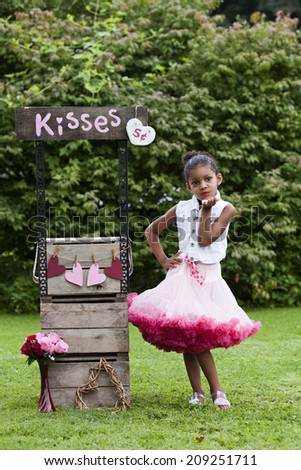 Kissing booth.  Adorable little girl standing next to a kissing booth.
