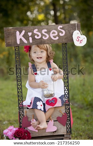 The Kissing Booth.  Adorable little girl sitting at a kissing booth.