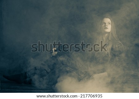Beautiful young woman in a fog.  Low lighting and fog to give a moody feel to the image. Editing includes some noise for effect.