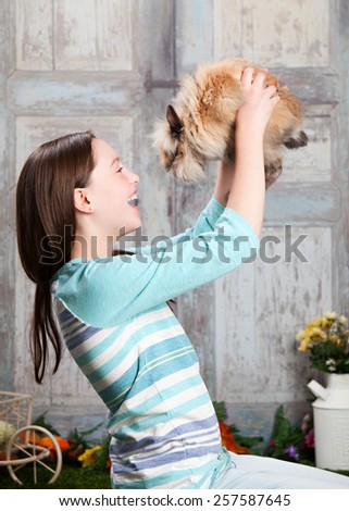 Attractive young girl playing with her pet bunny.