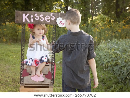 The Kissing Booth.  Adorable toddler collecting money from a boy wanting to buy a kiss from her.