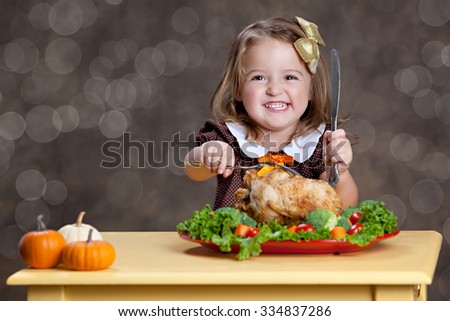 Thanksgiving Dinner.  Adorable little girl sitting at a small table with a small turkey (chicken) on a bed of greens and other vegetables.  Room for your text.