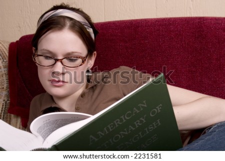 Attractive teen looking up a word in the American Dictionary of the English Language.