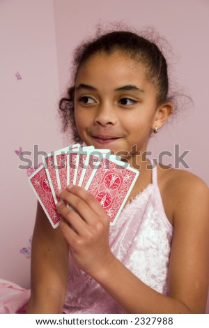 Adorable mulatto girl at a slumber party playing cards with her friends.