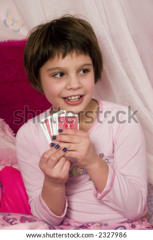 Adorable girl at a slumber party playing cards with her friends.