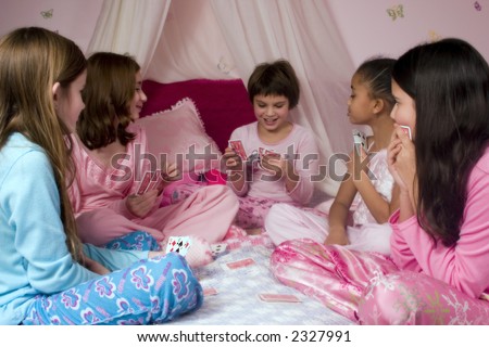 Five girls enjoying a game of cards at a slumber party.