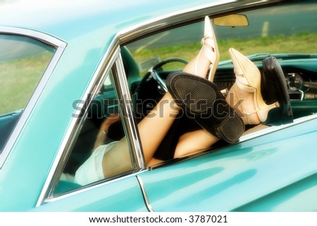 Legs and feet (with shoes) of a bride and groom protruding together from their car\'s back window.