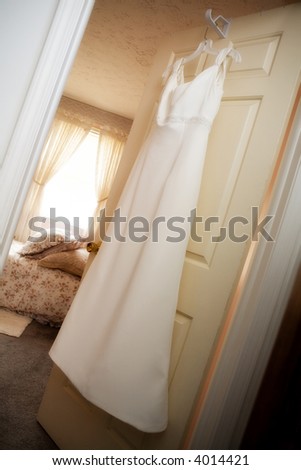 Wedding gown hanging in anticipation on a bedroom door.