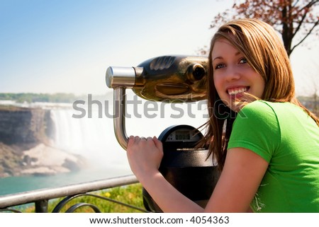Beautiful teen looking back from her view from the stationary binoculars at a scenic overlook.