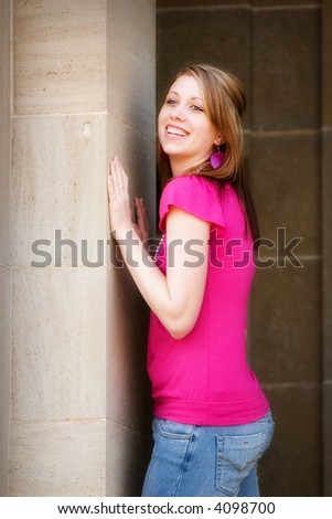 Portrait of a smiling teen pushing up against a school pillar.