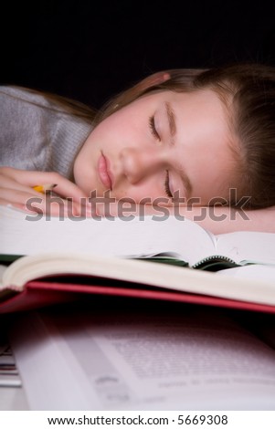 Exhausted middle school student asleep on her opened text books, a pencil still in her hand.