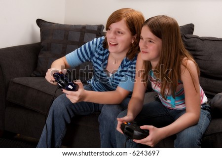 stock photo Two preteen girls playing an exciting video game at home