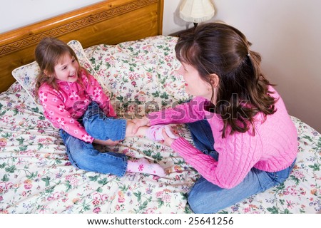 A mom and daughter playing on a big bed.