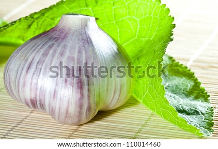 Garlic and green leaf of horseradish against bamboo background