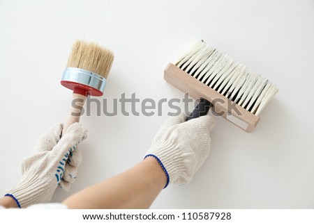 Hands holding construction paintbrushes - closeup shot