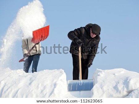 Snow removal: people working on a roof with snow shovels