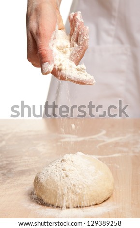 Woman's hand meals dough on wooden table; white background