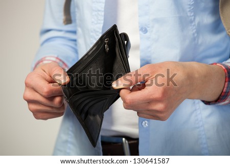 Female hands holding empty black purse; grey background