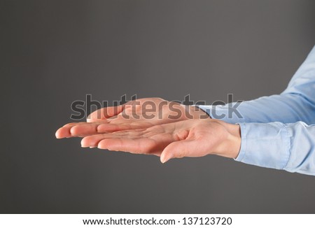 Woman's hands outstretched, grey background