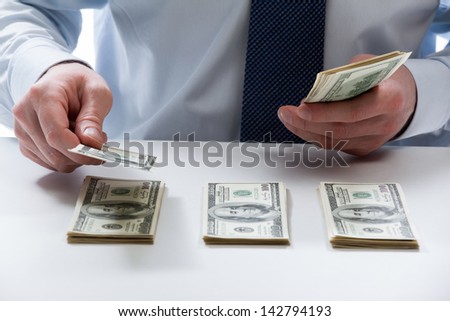 Bank teller\'s hands counting dollar banknotes on the table