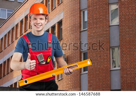 Friendly smiling construction worker in uniform showing thumbs up