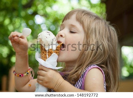 Pretty little girl eating an ice cream outdoors