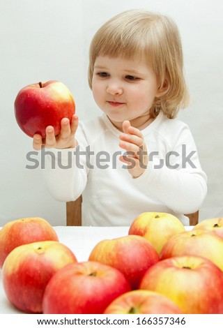 Smiling baby girl holding a big ripe  apple
