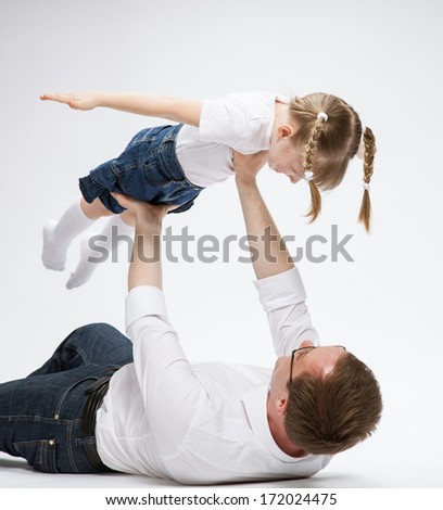 Happy young father playing with his smiling daughter neutral background Happy young father playing with his smiling daughter neutral background