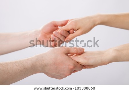 Two pairs of hands holding each other gently
