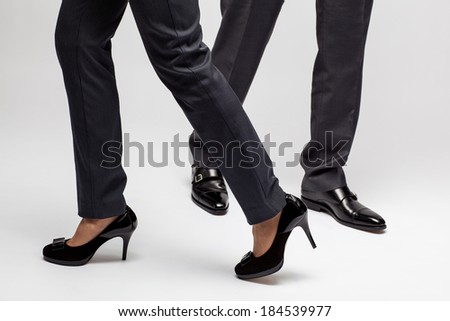 Male and female legs walking on grey background