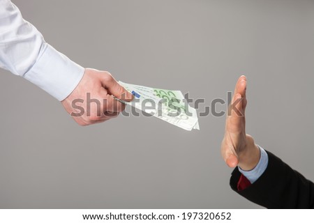 Businessperson\'s hand rejecting an offer of money on grey background