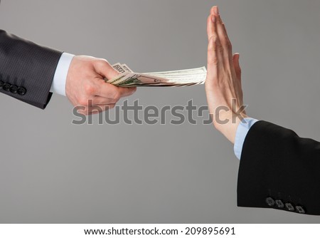 Businessperson\'s hand rejecting an offer of money on grey background