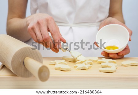 Unrecognizable cook spreading uncooked pastry with yolk