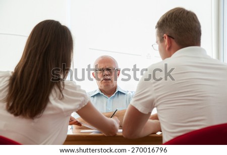 Strict boss sitting at the table and looking on his subjects
