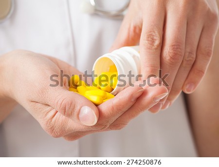 Doctor\'s pouring yellow tablets in the palm for a patient