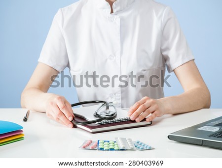 Unrecognizable doctor sitting at the table, blue background